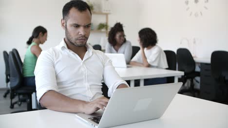 Nachdenklicher-Büroangestellter,-Der-Am-Tisch-Sitzt-Und-Einen-Laptop-Benutzt